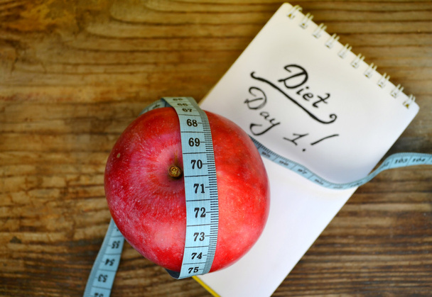 Concepto de dieta con manzana roja, un cuaderno y cinta métrica azul en la mesa de madera
 - Foto, imagen