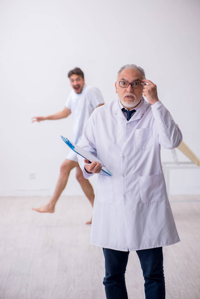 Yaşlı erkek doktor psikiyatrist genç erkek hastayı muayene ediyor. - Fotoğraf, Görsel