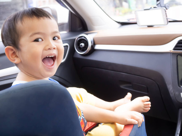 Cute little boy smile and sitting in car seat with blur mock up mobile phone. child happy and smile. learning age or family tourist travel in holidays, transportation concept. - Photo, Image
