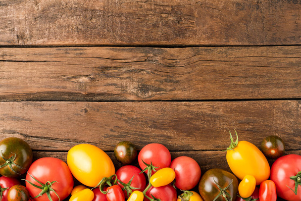 Overhead shot of red, yellow and green tomatoes on rustic table with copyspace. Food background. Top view - Foto, Imagem