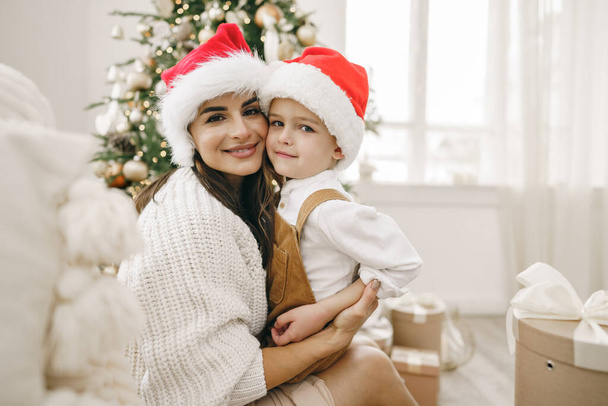 Porträt einer glücklichen Mutter und ihres Sohnes feiern Weihnachten in festlich geschmücktem Raum - Foto, Bild