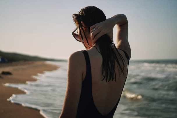 woman in black swimsuit walking on the beach ocean summer - Foto, Bild
