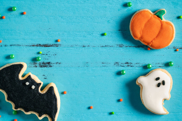 Vista superior de las galletas de azúcar de jengibre horneadas decoradas festivas de Halloween sobre fondo azul con espacio de copia y puesta plana. - Foto, imagen