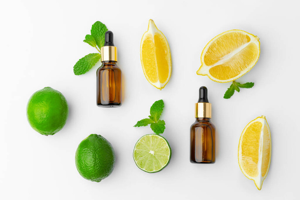 Essential oil bottles and citrus fruit on white background - Zdjęcie, obraz