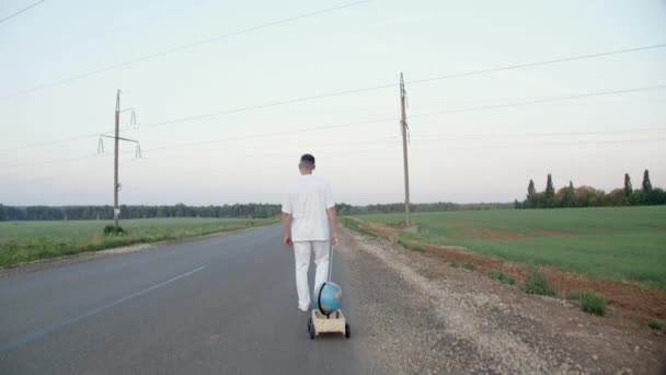 Images de l'homme pieds nus traînant un chariot en bois avec globe - Séquence, vidéo