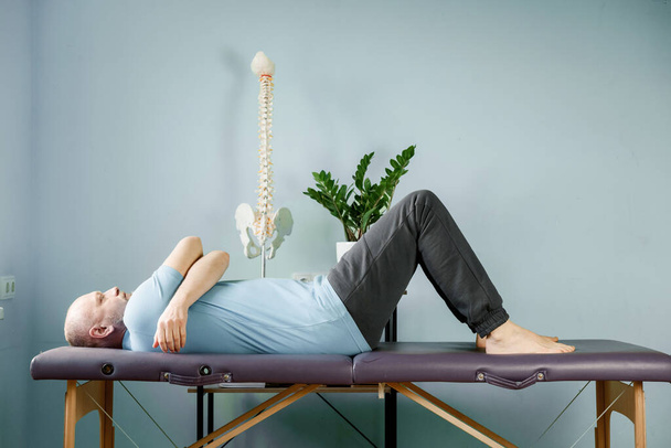 建設的な休憩所のマッサージテーブルの上に横たわる男, si関節痛救済 - 写真・画像