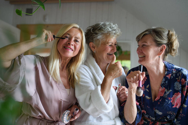 Boldog idősebb nők barátok fürdőköpenyben csinál töltsük ki beltéri otthon, önellátás koncepció. - Fotó, kép
