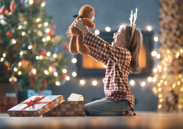 Merry Christmas and Happy Holidays! Cheerful cute child girl with gift. Kid is having fun near tree.     - Фото, зображення