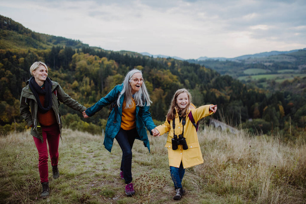 Small girl with mother and grandmother hiking outoors in nature. - 写真・画像