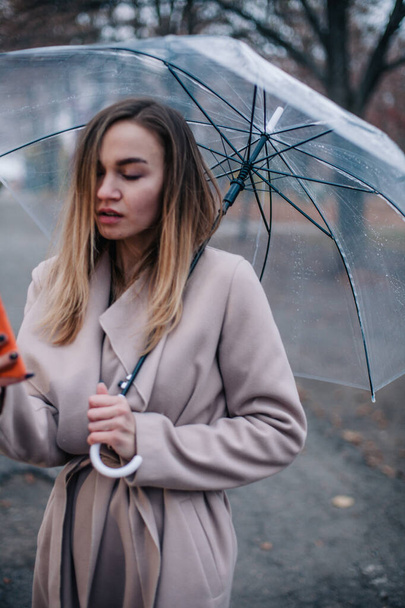 Happy young girl with a transparent umbrella takes a selfie on a rainy day - Valokuva, kuva