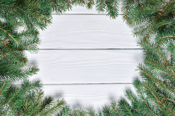 Top view of a frame of fir branches on a white wooden table.New Year greeting card. A mock-up of a Christmas greeting. Copy space. Flat lay. - Foto, Bild