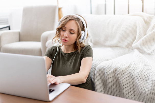 Woman with glasses use laptop sitting floor near  sofa big window background home interior Frelance female working home Distance learning student relaxing wathcing video lesson - Foto, Imagem