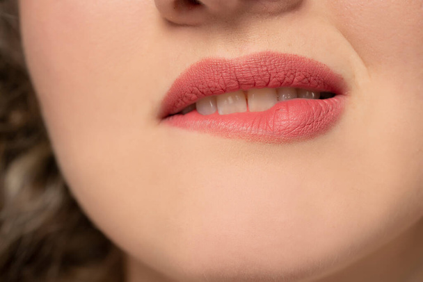 Closeup of woman biting her lips with matte lipstick - Photo, Image