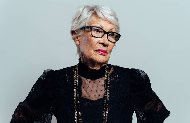 image of a beautiful and elegant old influencer woman. Cool grandmother posing in studio wearing fashionable clothes - Valokuva, kuva