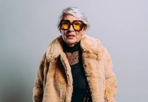 image of a beautiful and elegant old influencer woman. Cool grandmother posing in studio wearing fashionable clothes - Valokuva, kuva