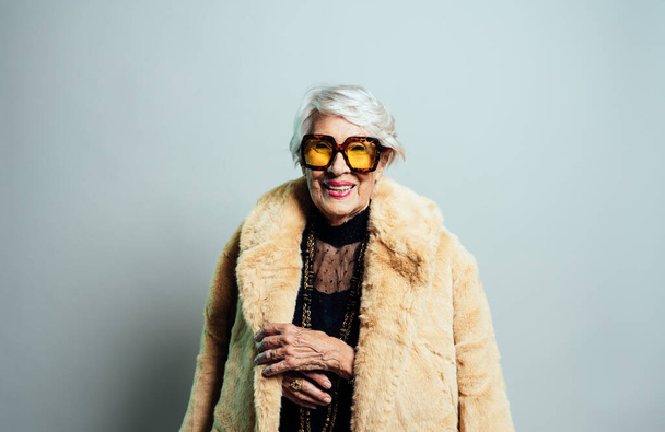 image of a beautiful and elegant old influencer woman. Cool grandmother posing in studio wearing fashionable clothes - Zdjęcie, obraz