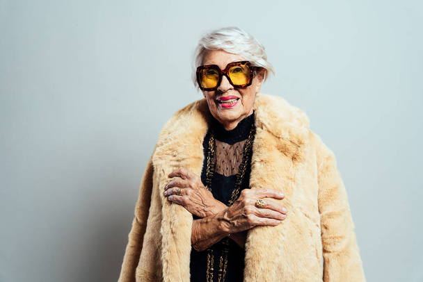 image of a beautiful and elegant old influencer woman. Cool grandmother posing in studio wearing fashionable clothes - Zdjęcie, obraz