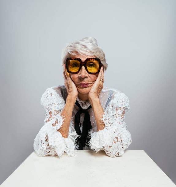 beautiful and elegant old influencer woman. Cool grandmother posing in studio wearing fashionable clothes. Happy senior lady celebrating and making party. Concept about seniority and lifestyle - Foto, Imagem