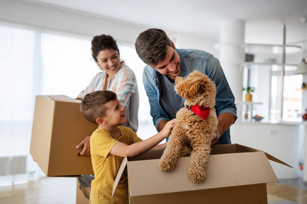 Family unpacking cardboard boxes at new home. New house, family, insurance concept. - Zdjęcie, obraz