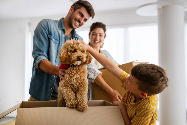 Husband and wife and their son with dog moving in new home. Family, relocation, moving in concept. - 写真・画像