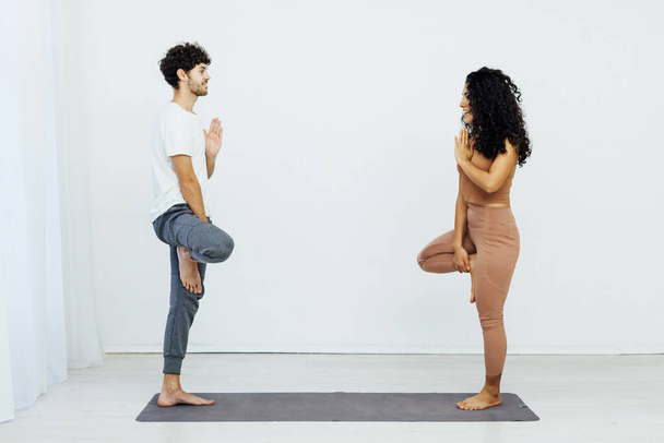 une femme et un homme pratiquent un yoga asana jumelé dans une chambre blanche - Photo, image