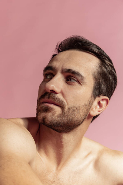Close-up portrait of young handsome bearded shirtless man isolated on pink studio background. Natural beauty - Valokuva, kuva