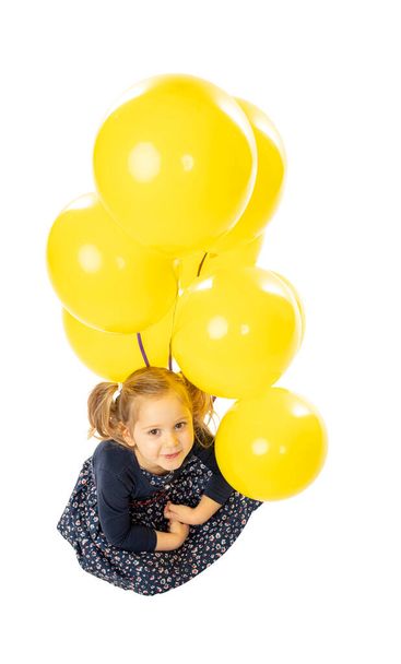 blond caucasian little girl with yellow balloons isolated on white. - Fotó, kép