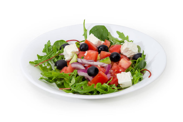 Vegetable salad with feta cheese, known as Greek salad on the white dish on a white background - Fotó, kép
