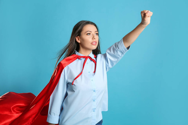 Confident young woman wearing superhero cape on light blue background - Fotoğraf, Görsel