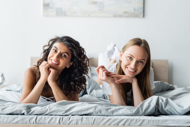 vrolijke lesbische vrouwen liggend op bed thuis - Foto, afbeelding