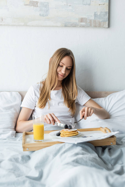pleased woman having breakfast in bed  - Фото, изображение