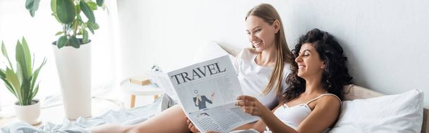 happy lesbian couple reading travel newspaper in bedroom, banner - Photo, Image