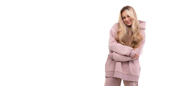 blonde in a tracksuit on a white background with a smile on her face - Foto, Imagen