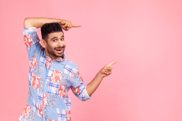 Wow, attention to advertising! Portrait of happy bearded man pointing to side copy space with both hands and showing blank wall for idea presentation. Indoor studio shot isolated on pink background. - Valokuva, kuva