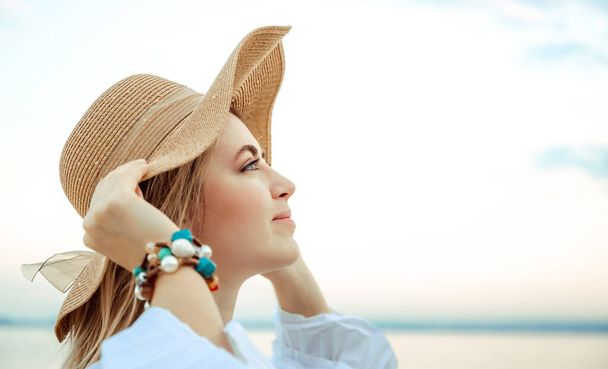 Portrait of beautiful young 30 years woman caucasian appearance in straw hat with satin ribbon bow. Copy space. Close-up. Attractive girl. Summer lifestyle concept. Natural background. Elegant style. - Photo, Image