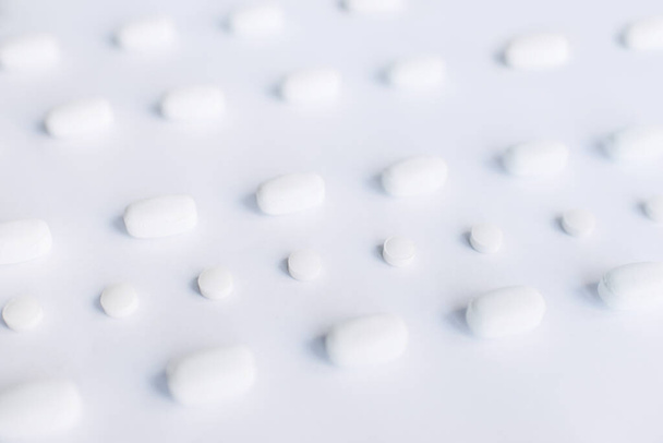 White pills on a white background. Oblong and round pills close-up. Healthcare and medicine. - Foto, immagini
