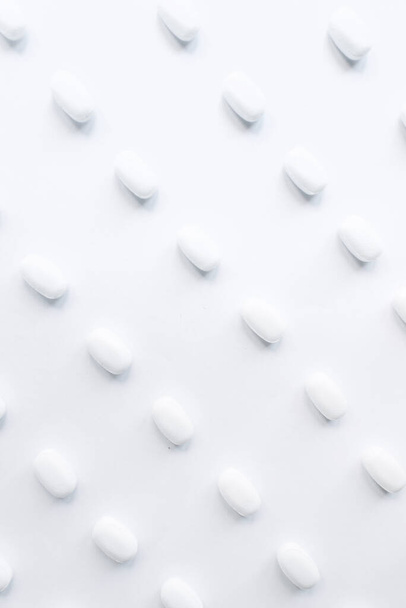 White pills on a white background. Oblong and round pills close-up. Healthcare and medicine. - 写真・画像