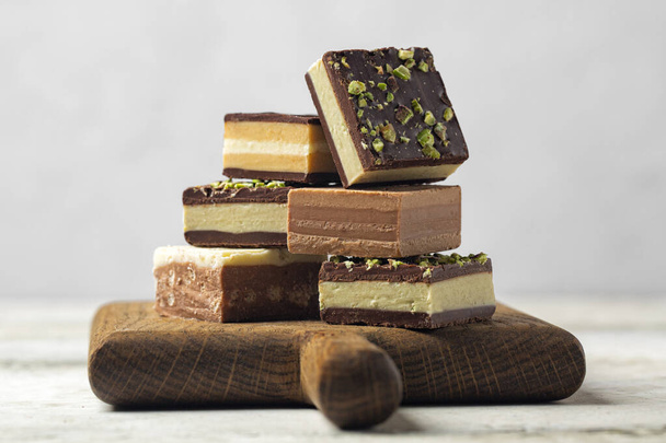 Variety of cremino - italian chocolate,  originally from Piedmont, composed by different layers, made with gianduja chocolate, coffee, pistacchio or hazelnut paste. On light background. - Photo, Image