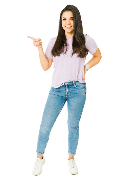 Volledige lengte van een mooie jonge vrouw bevorderen van een verkoop advertentie en wijzen met haar vinger om ruimte te kopiëren - Foto, afbeelding