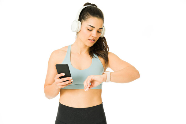 Mujer joven enfocada usando una aplicación de salud en su smartwatch y contando calorías para su entrenamiento  - Foto, Imagen