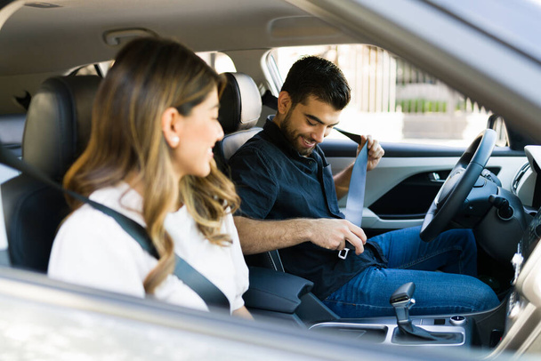 La seguridad primero. Feliz hombre y su novia en el coche ponerse el cinturón de seguridad antes de conducir a casa - Foto, Imagen