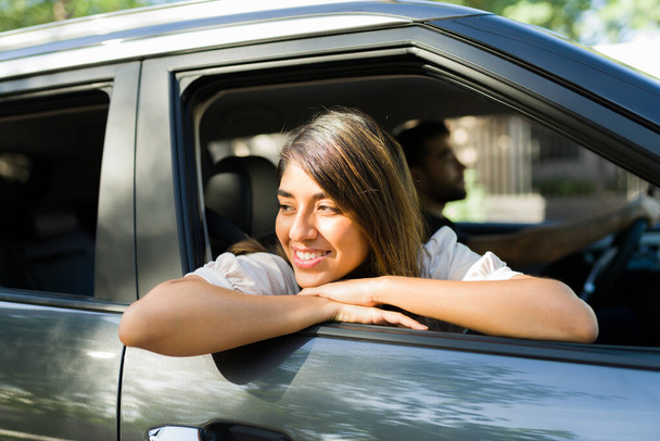 Красивая молодая женщина, выглядывающая из окна автомобиля и наслаждающаяся видом во время поездки по дороге  - Фото, изображение