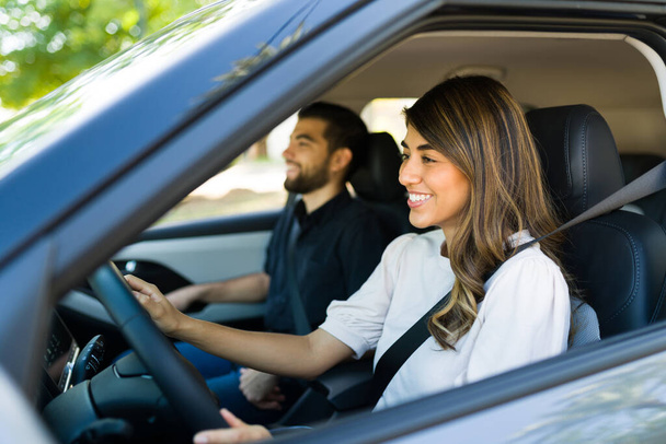 Счастливая молодая женщина водит машину со своим парнем и улыбается во время дорожной поездки  - Фото, изображение