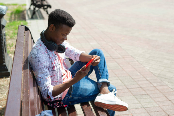 young african man with mobile phone on bench - Fotó, kép