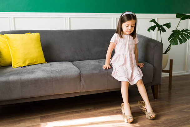 ドレスアップをプレイ。愛らしいです5歳の女の子置く上の彼女のお母さんの靴とともにヒールで家の周りに遊ぶ  - 写真・画像