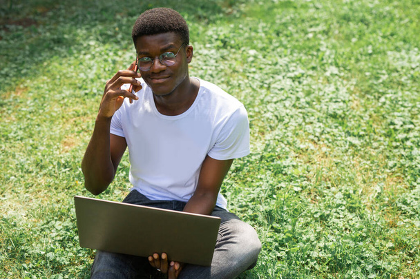 Cep telefonu ve dizüstü bilgisayarı olan genç Afrikalı bir erkek. - Fotoğraf, Görsel