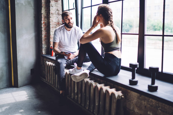Caucasian male and female friends having conversation in guy after training discussing healthy lifestyle, woman asking questions her trainer during consultancy about losing weight and slimming - Foto, Bild