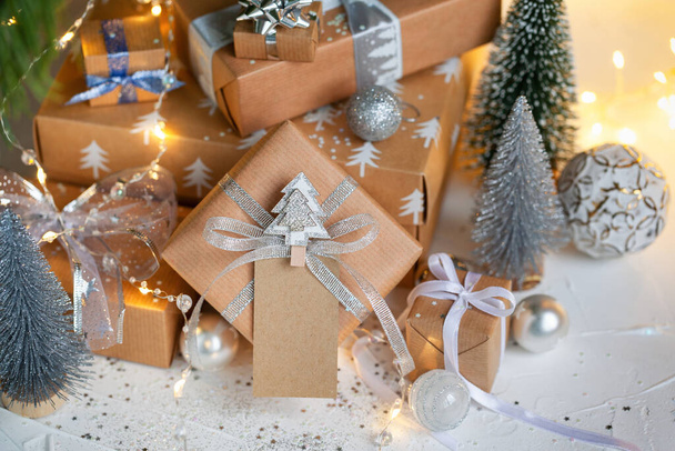Festive zero waste gift boxes under Christmas tree in the home interior of the living room. Preparation of gifts to relatives. New year holiday cozy, mood festive concept. - 写真・画像
