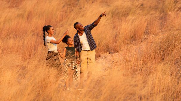 Soft and select focus. Happy African family father mother and child daughter travel and running on meadow nature on silhouette lights sunset.  Travel and Family Concept - Фото, зображення