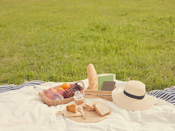 ピクニックのコンセプトパン、果物、水のボトル、帽子、ノートブックなど、白い布には多くのことがあります。. - 写真・画像